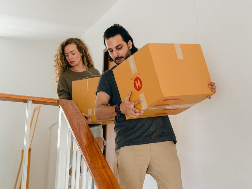 focused diverse couple carrying boxes downstairs at home