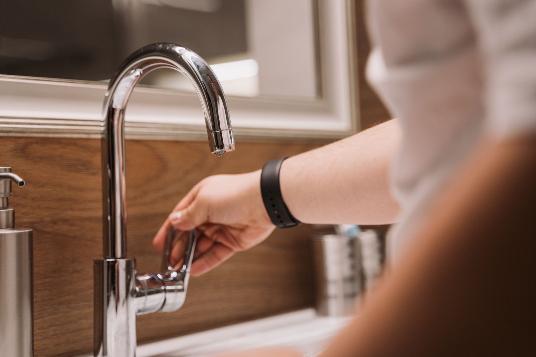 a person turning a faucet handle