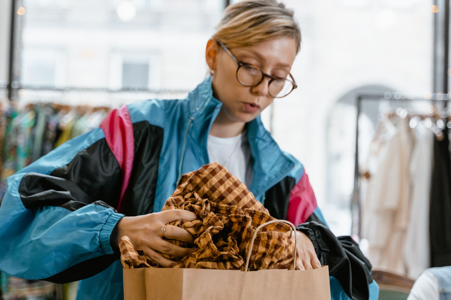 woman in blue jacket putting clothes in brown paper bag | GenadePro